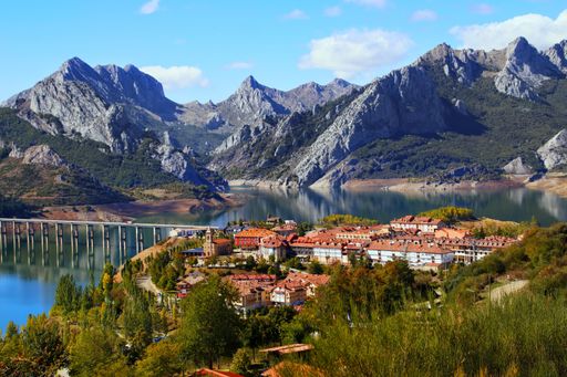 An awesome shot of a small village by the river and mountains in the background in Riano reservoir Leon Spain