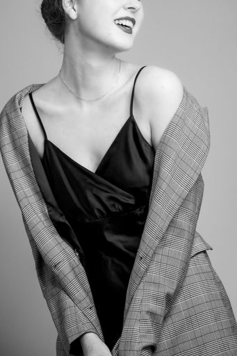 A vertical grayscale shot of an elegant female posing in a slip dress and a blazer