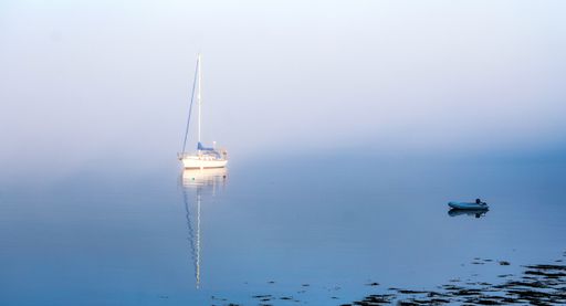 A beautiful shot of a sloop emerging from the early morning mist in Northwest Harbor in Deer Isle