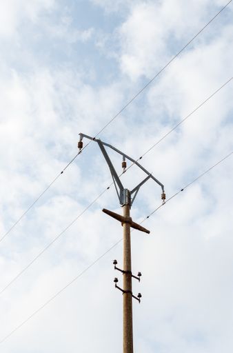 A vertical shot of an electrical post under the sky