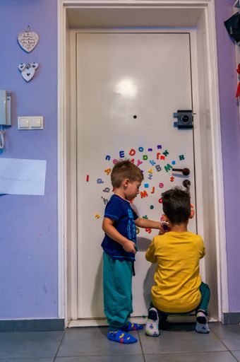 Two boys attaching magnet letters to a door