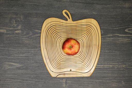 A top view of a red apple on an apple-shaped wooden mat