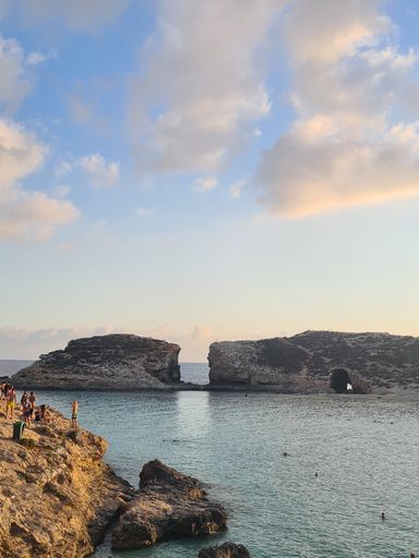 A vertical shot of a small cliff on the coast of a beach during a beautiful sunset