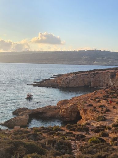 A vertical shot of a small cliff on the coast of a beach during a beautiful sunset