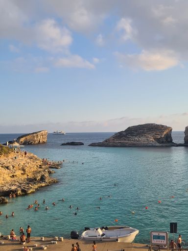 A vertical shot of the coast of an ocean with a cliff on a sunny day