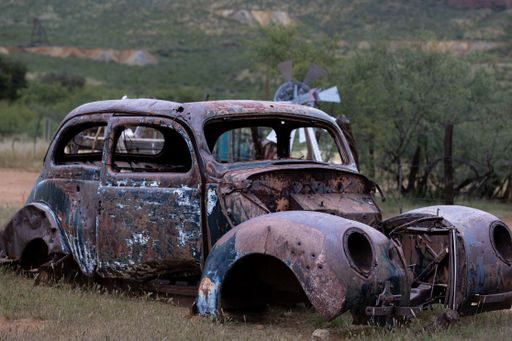 A vintage rusty old abandoned car decaying on a rural field