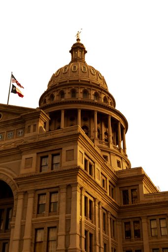A vertical shot of the beautiful Texas Capitol dome with the US and Texas flags