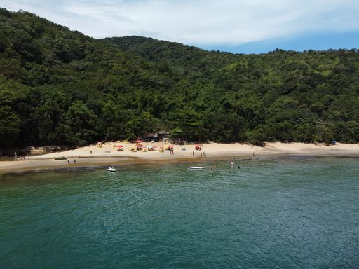 An aerial shot of the Da Barra Do Sahy sandy beach with vacationers near the clear sea