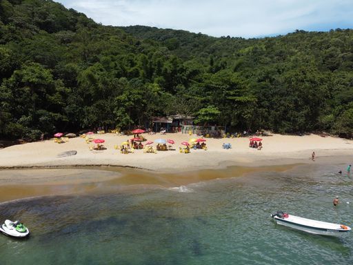 An aerial shot of the Da Barra Do Sahy sandy beach with vacationers near the clear sea
