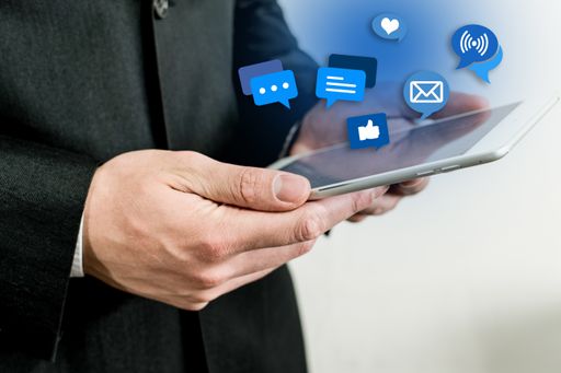 A closeup of a male holding a tablet with social media icons above it
