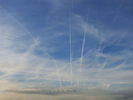 Airplanes trails and lines on the blue cloudy sky