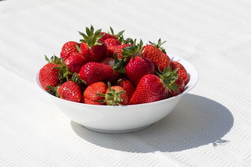 Fresh strawberries in a white bowl on a table