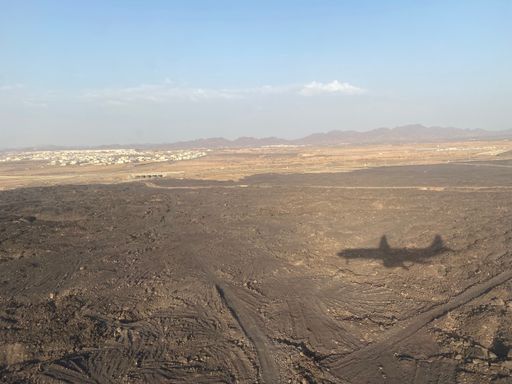 An aerial view of a desert landscape seen from an airplane with shadow on the ground