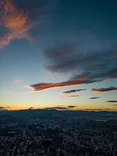 A mesmerizing sunset over a city surrounded by mountainous landscape, vertical