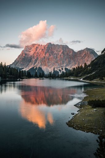 A vertical shot of a lake surrounded by rocky hills during the sunset in Austria