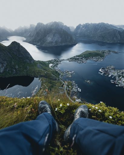 A vertical shot of a small village surrounded by greenery and rocky mountains in Lofoten, Norway