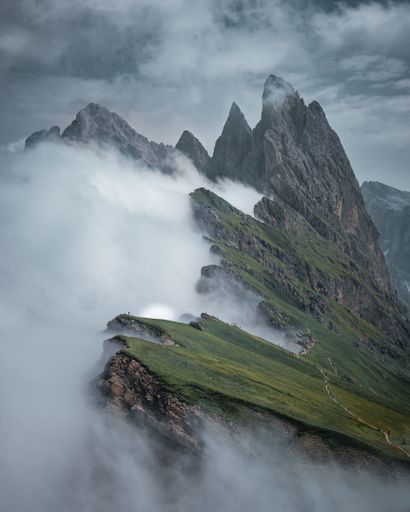 A vertical shot of the Seceda mountain covered in the fog in winter in Italy