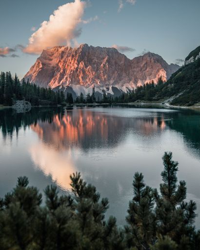 A vertical shot of a lake surrounded by rocky hills during the sunset in Austria