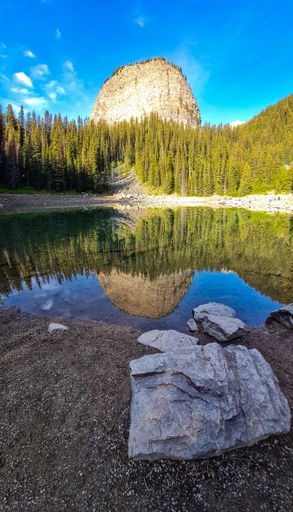 A vertical shot of a clear lake near trees and a cliff in Banff national Park in Alberta, Canada