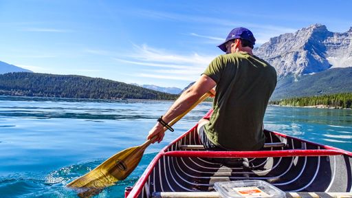 A back view of a male in a canoe rowing on a lake in Banff National Park