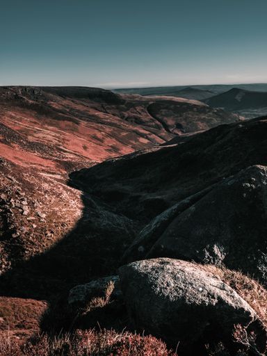 A vertical shot of rocky mountains stretching towards the horizon under blue sky