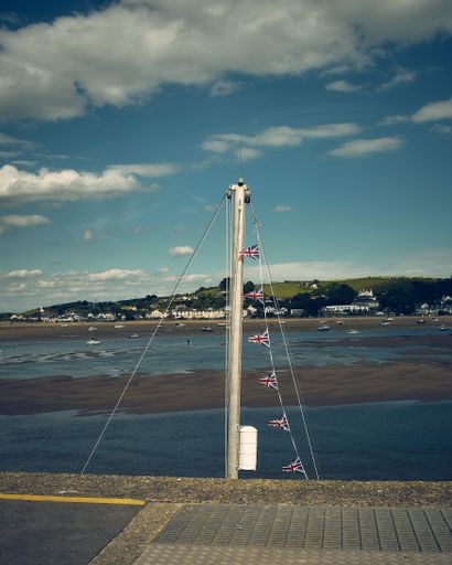 A vertical shot of the sailboat mast with small British flags seen from the promenade