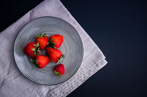 A top view shot of strawberries on a plate isolated on a blue background with copy space