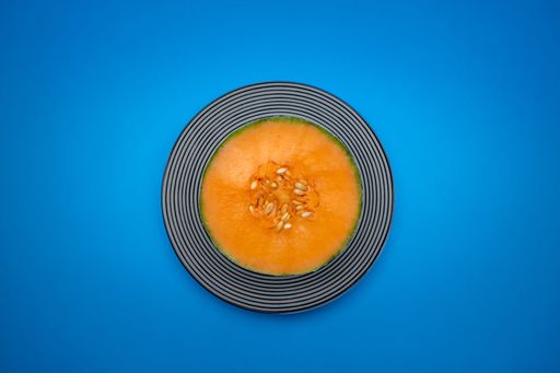 A top view shot of a half-cut papaya on a plate isolated on a blue background with copy space