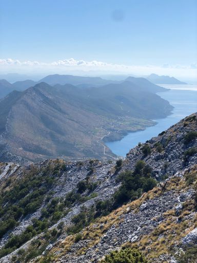 A mountain landscape overlooking the sea and cloudy blue sky