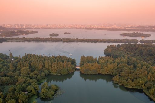 An aerial view of a beautiful landscape with a lake and lush green nature at sunset in Hangzhou
