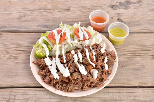 A top view of a traditional grilled beef on a plate served with sauces on a wooden table