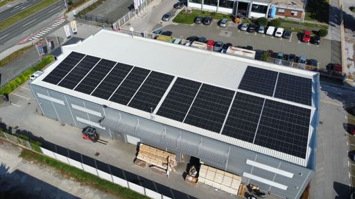 An aerial view of a building's roof with solar panels on a sunny day