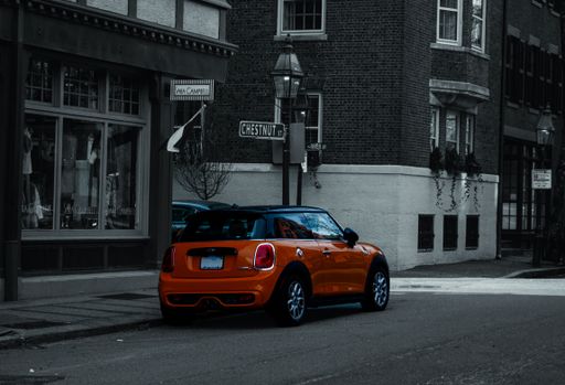 A selective color shot of an orange Mini Cooper car on the side of a street in Boston, USA