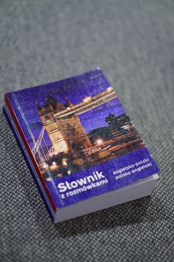 A top view of Polish to English dictionary laying on a gray sofa with blur background