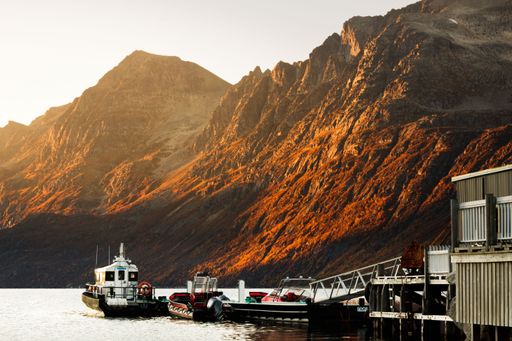A landscape view of the Fjord with a few boats on the water at sunset