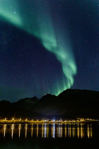 A vertical shot of Northern Lights over the mountains in Norway during the stary night