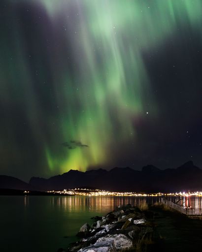 A vertical shot of Northern Lights over the mountains in Norway during the stary night