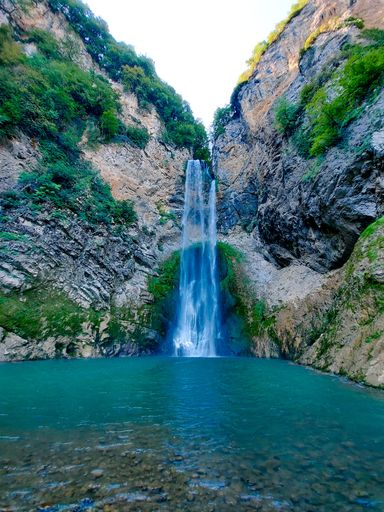A vertical shot of the waterfall flowing between the rocky formations