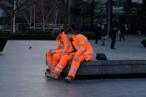 Two men workers wearing orange uniform and taking a lunch break in London