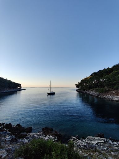 A vertical shot of a sailboat on a blue calm river
