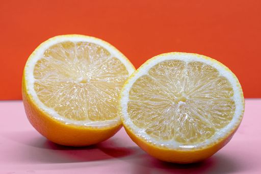A closeup shot of a halved lemon on an orange background