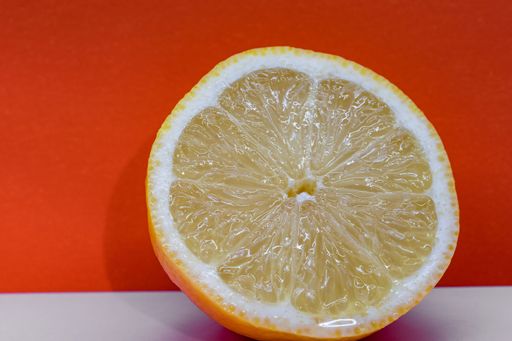 A closeup shot of half a lemon isolated on an orange background