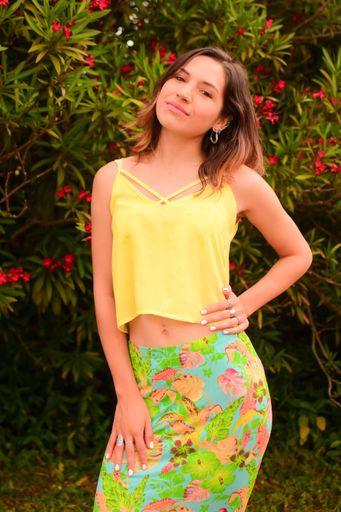 A vertical shot of a beautiful, young Hispanic lady posing for a picture in a park in daylight
