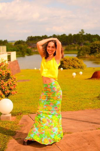 A vertical shot of a beautiful, young Hispanic lady posing for a picture in a park in daylight