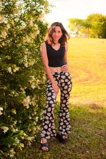 A vertical shot of a beautiful, young Hispanic lady posing for a picture in a park in daylight
