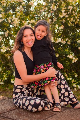 A vertical shot of a young kid with her mom posing in a park in daylight