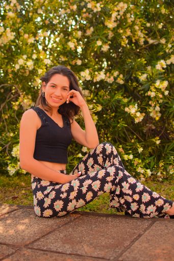 A vertical shot of a beautiful, young Hispanic lady posing for a picture in a park in daylight