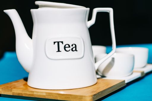 A closeup shot of teacups set with a kettle on a blue background