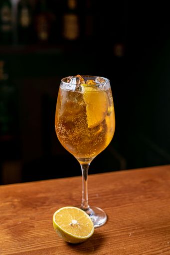 A glass of Aperol spritz cocktail with lemon slices on a bar counter