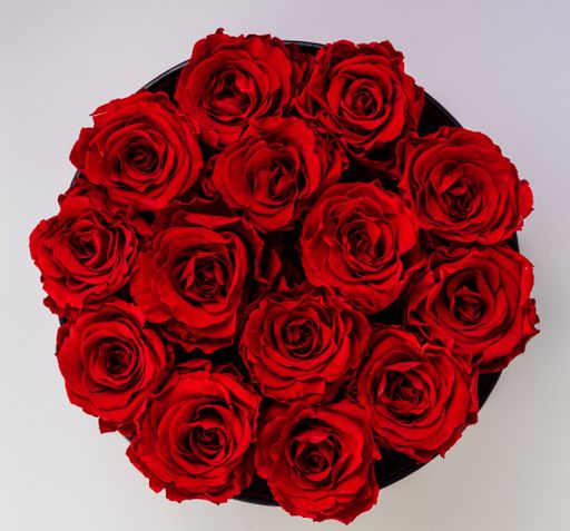 A bouquet of red roses with a light pink background shot from above